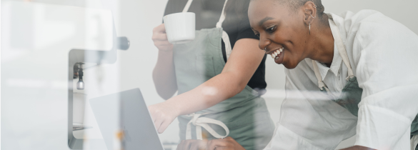 Lady leaning over working on a laptop while someone points at what she is doing